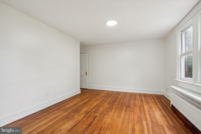 spare room featuring dark hardwood / wood-style flooring and radiator