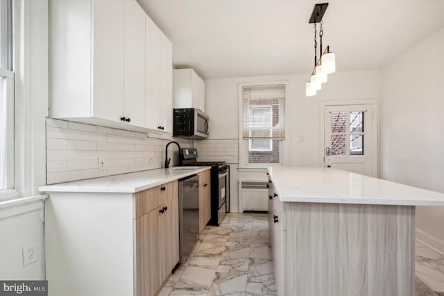 kitchen featuring a center island, white cabinets, pendant lighting, appliances with stainless steel finishes, and backsplash