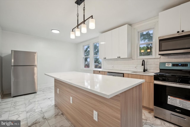 kitchen featuring stainless steel appliances, hanging light fixtures, a center island, and white cabinetry