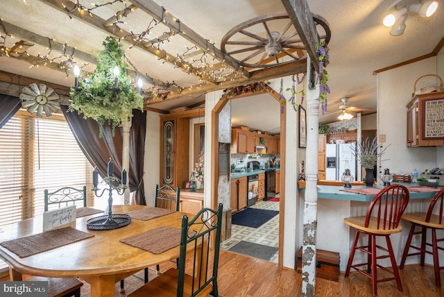 dining area with wood finished floors, beamed ceiling, and a ceiling fan