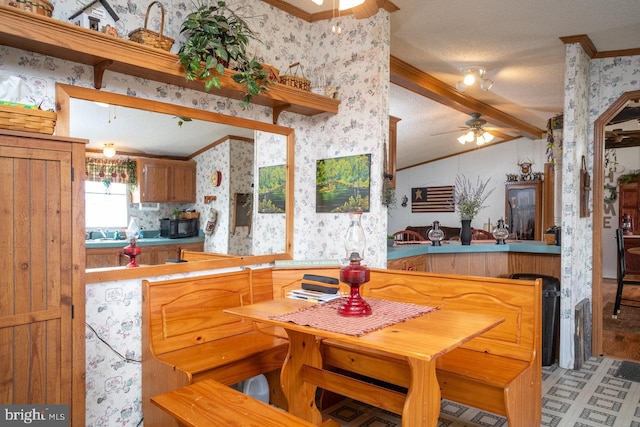 dining space with ceiling fan, a textured ceiling, lofted ceiling with beams, and ornamental molding