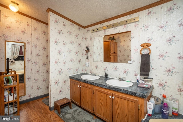 bathroom featuring a textured ceiling, wallpapered walls, and a sink
