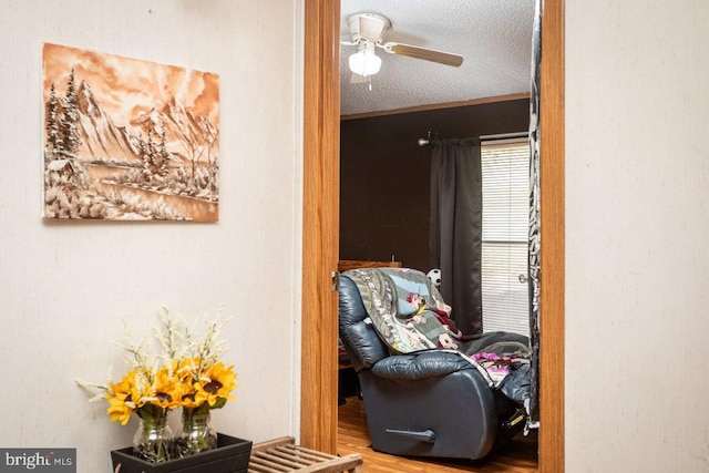 interior space featuring ceiling fan, a textured ceiling, ornamental molding, and hardwood / wood-style flooring