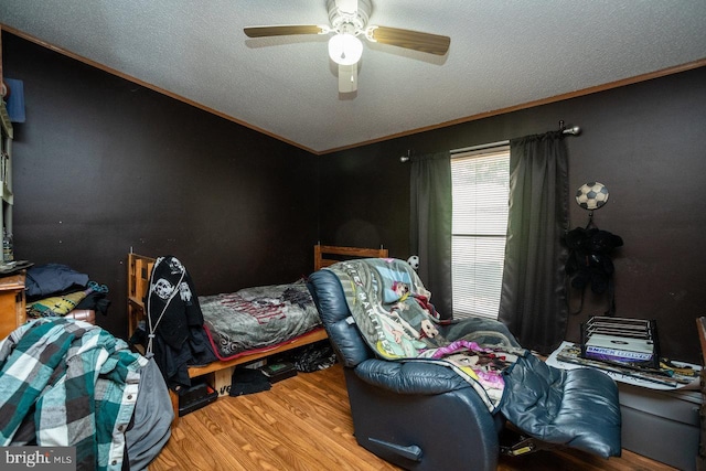 bedroom featuring crown molding, a ceiling fan, wood finished floors, and a textured ceiling
