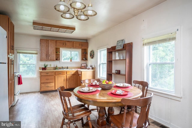 dining area featuring an inviting chandelier, a wealth of natural light, hardwood / wood-style floors, and sink