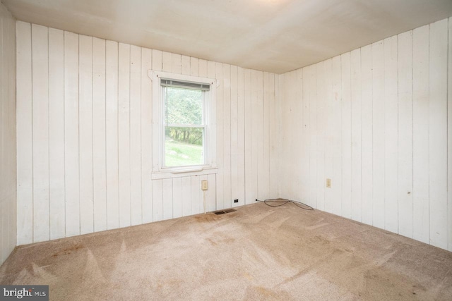 unfurnished room featuring carpet floors and wood walls