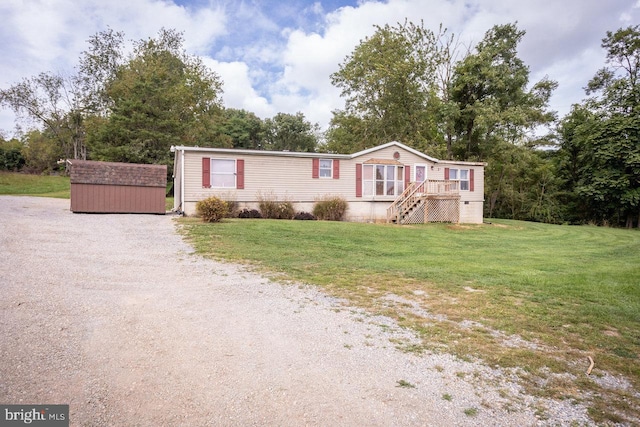 manufactured / mobile home featuring a storage shed, an outbuilding, driveway, and a front lawn