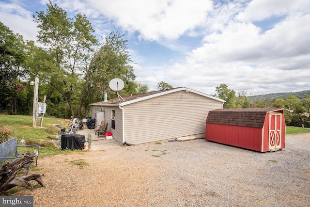 view of home's exterior featuring roof with shingles, an outbuilding, and a storage unit