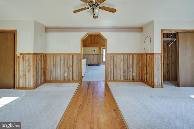 empty room with wooden walls, ceiling fan, and light hardwood / wood-style flooring