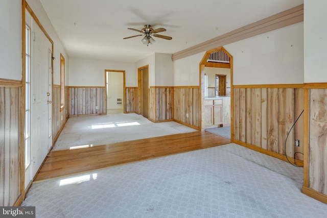 unfurnished room with ceiling fan, wooden walls, and light hardwood / wood-style floors