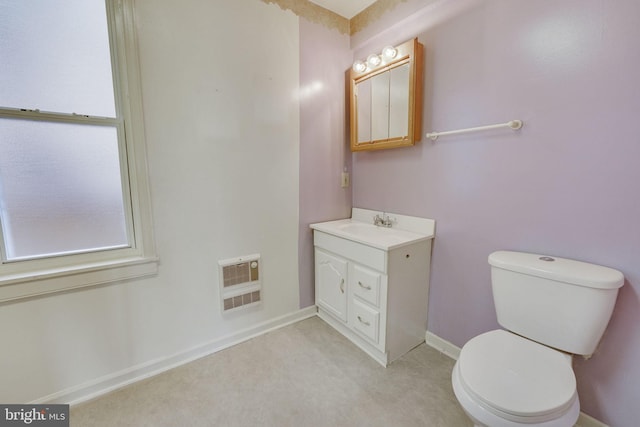 bathroom with vanity, heating unit, and toilet