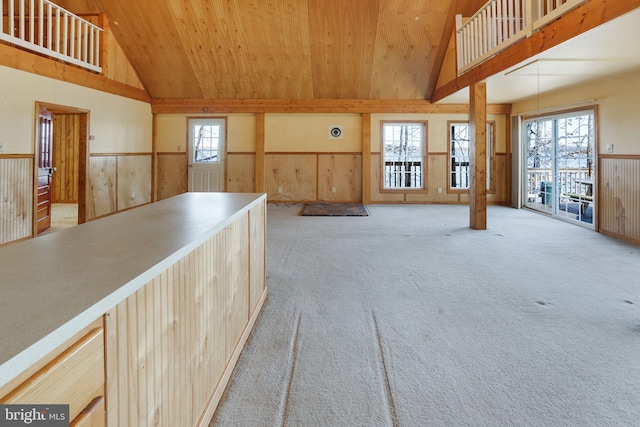 interior space with wooden walls, light carpet, and high vaulted ceiling