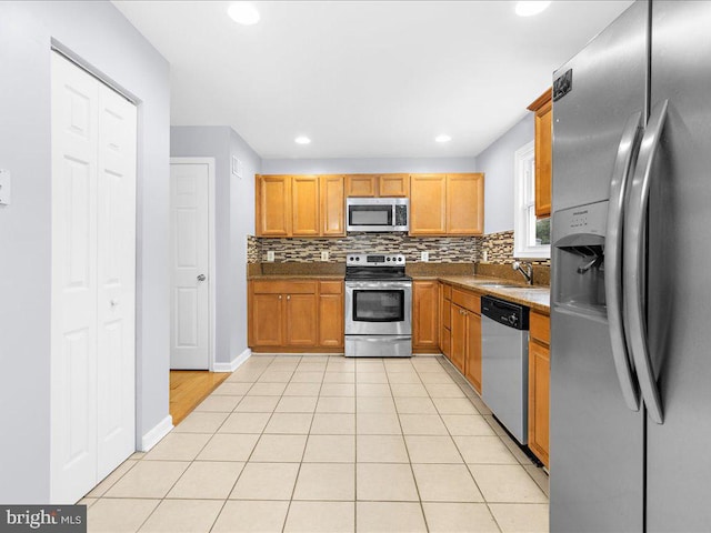 kitchen with decorative backsplash, appliances with stainless steel finishes, light tile patterned floors, and sink