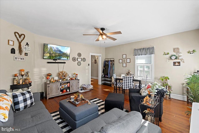 living room featuring ceiling fan and dark wood-type flooring