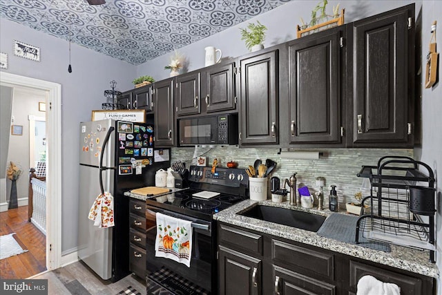 kitchen featuring backsplash, light stone countertops, black appliances, dark hardwood / wood-style floors, and sink