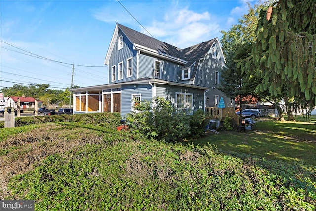 view of side of property with a sunroom and a yard