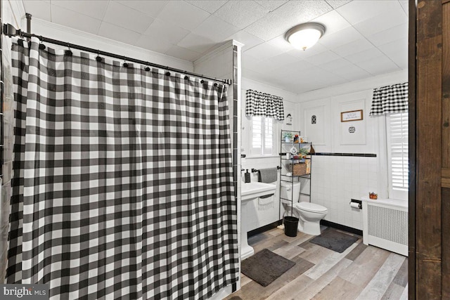 bathroom featuring tile walls, radiator heating unit, wood-type flooring, ornamental molding, and toilet