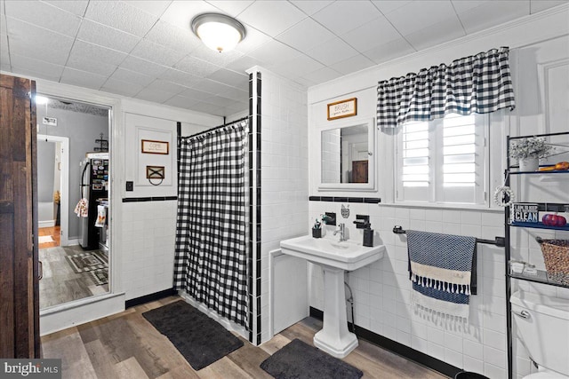 bathroom featuring tile walls, ornamental molding, hardwood / wood-style floors, and a shower with shower curtain