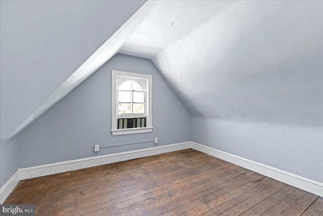 additional living space featuring vaulted ceiling and dark hardwood / wood-style flooring