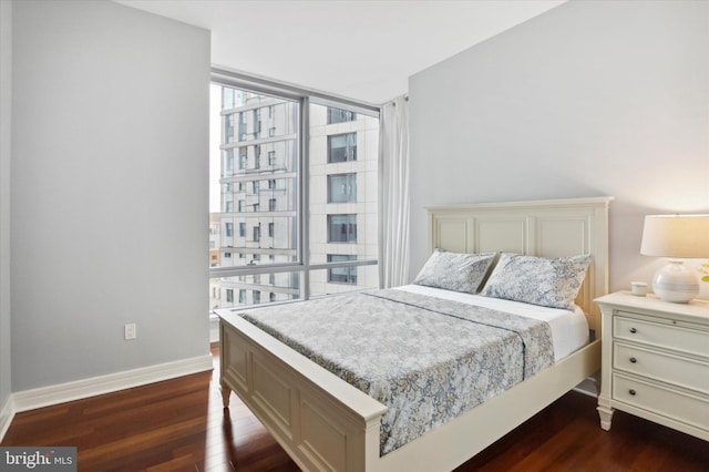 bedroom featuring a wall of windows and dark hardwood / wood-style floors