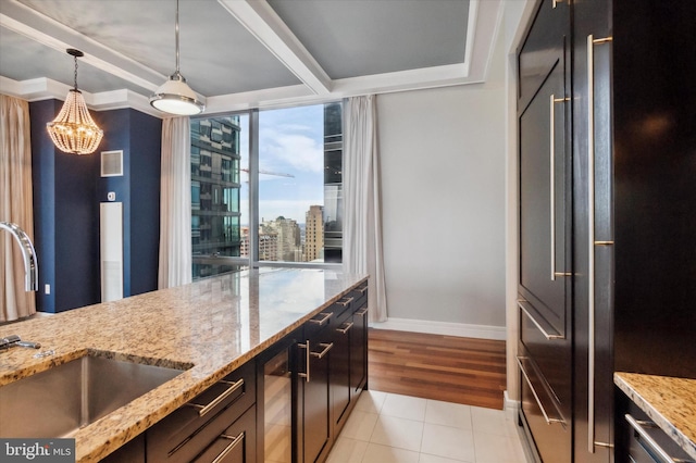 kitchen featuring light stone countertops, pendant lighting, beverage cooler, light hardwood / wood-style flooring, and sink