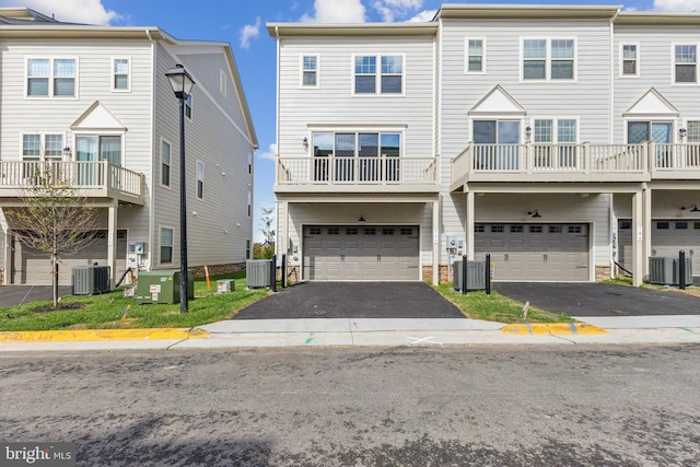 townhome / multi-family property featuring a balcony, central AC unit, and a garage