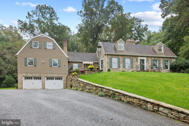 cape cod home with a front yard and a garage