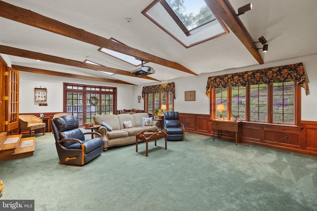 living room with lofted ceiling with skylight, carpet floors, and wood walls