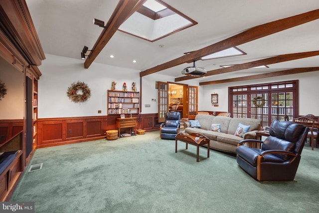 living room with french doors, beamed ceiling, a skylight, and carpet