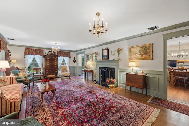 living room with a notable chandelier, dark hardwood / wood-style floors, and ornamental molding