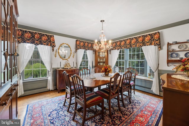 dining area featuring crown molding, a chandelier, light wood-type flooring, and a baseboard radiator