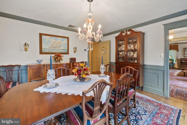 dining space with an inviting chandelier, crown molding, and light hardwood / wood-style floors