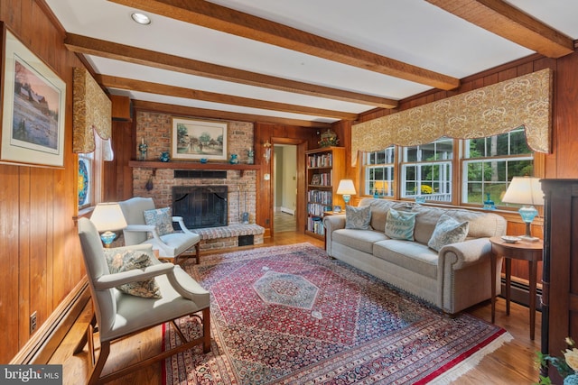 living room with wood-type flooring, beam ceiling, a brick fireplace, and wooden walls