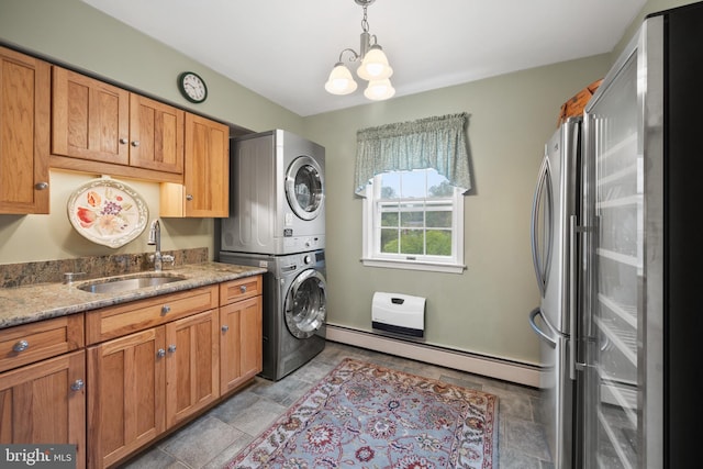 laundry room featuring stacked washer / drying machine, an inviting chandelier, sink, and a baseboard heating unit