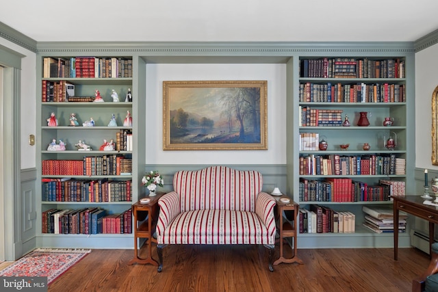 living area with built in features, ornamental molding, hardwood / wood-style floors, and a baseboard radiator