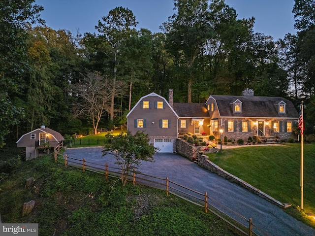 new england style home featuring a garage and a yard