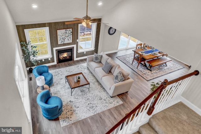 living room featuring wood-type flooring, wooden walls, lofted ceiling, and ceiling fan