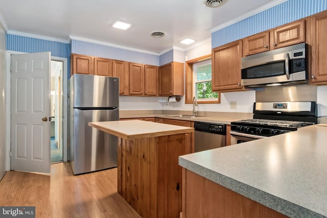 kitchen with ornamental molding, sink, light hardwood / wood-style flooring, and stainless steel appliances