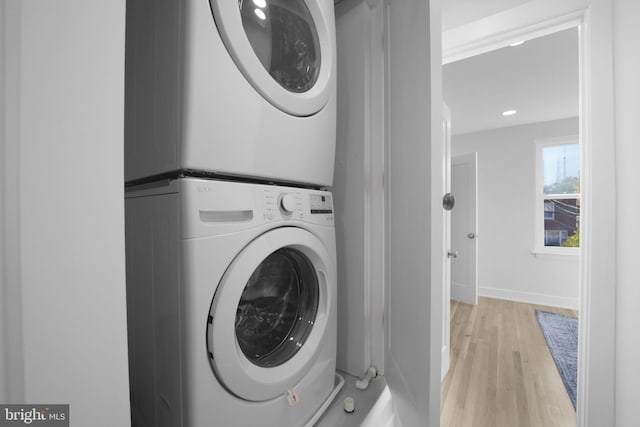 laundry room with light hardwood / wood-style floors and stacked washer and dryer