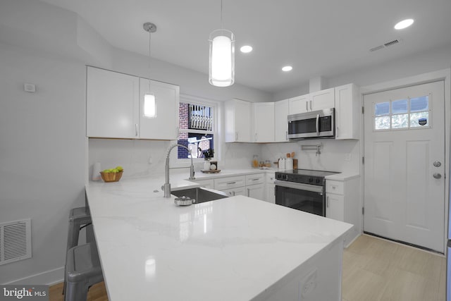 kitchen with white cabinetry, electric range, sink, kitchen peninsula, and decorative light fixtures