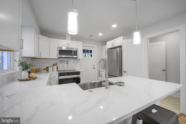 kitchen with pendant lighting, white cabinets, kitchen peninsula, and stainless steel appliances