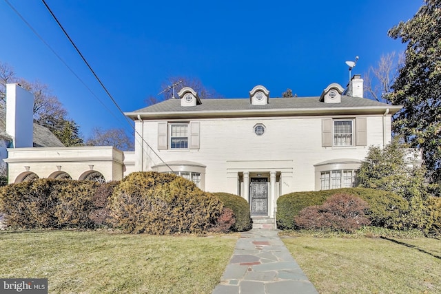 view of front facade featuring a chimney and a front yard