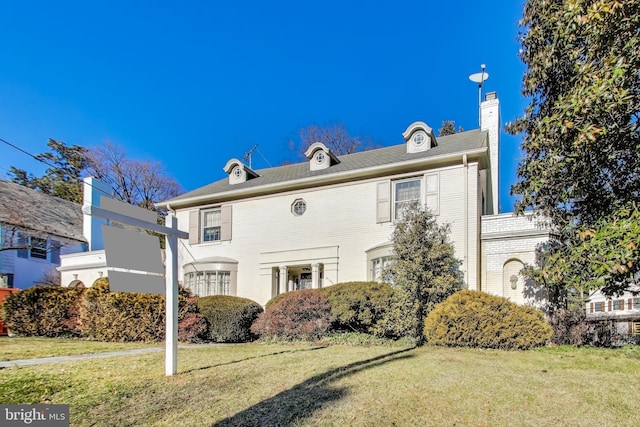 back of property featuring brick siding, a chimney, and a yard