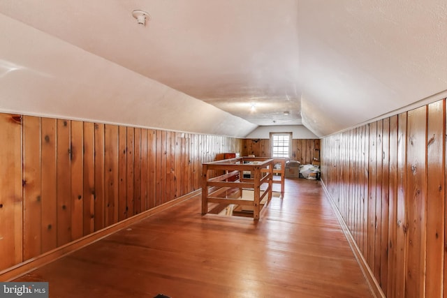 bonus room with lofted ceiling, wooden walls, and wood finished floors