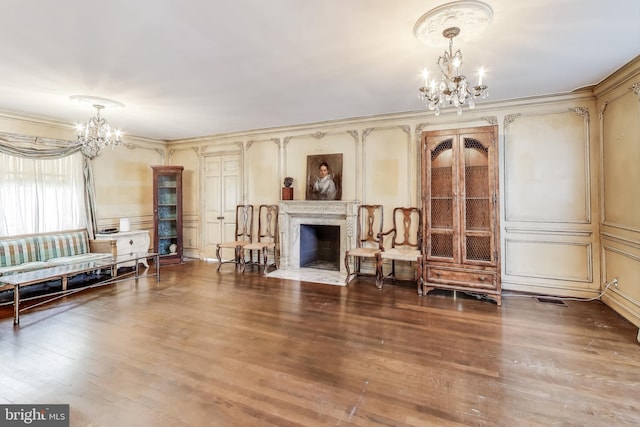 living area featuring a notable chandelier, a decorative wall, a fireplace with flush hearth, and wood finished floors