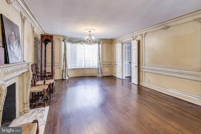 living area with a premium fireplace, a chandelier, dark wood finished floors, and crown molding