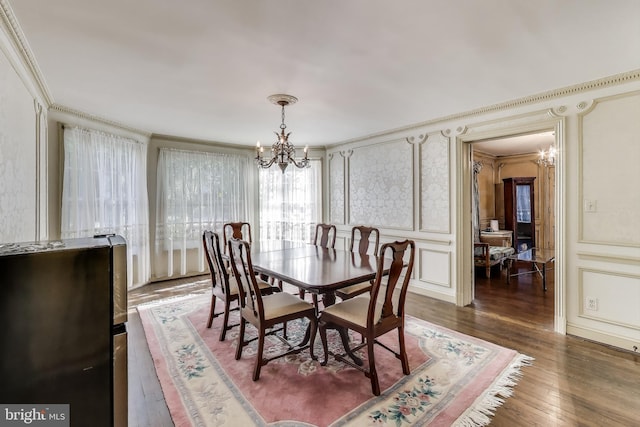 dining room featuring hardwood / wood-style floors, an inviting chandelier, a decorative wall, and ornamental molding