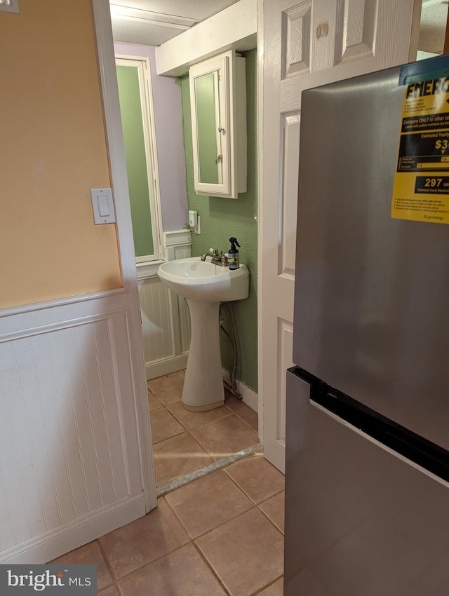bathroom featuring a sink, tile patterned floors, and a wainscoted wall
