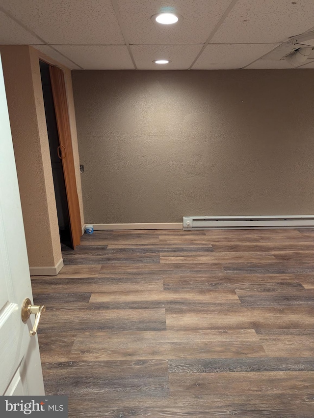 interior space featuring a baseboard radiator, baseboards, a paneled ceiling, and wood finished floors