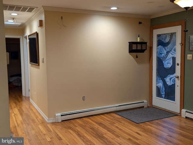 foyer entrance featuring light wood-type flooring, ornamental molding, visible vents, a baseboard heating unit, and baseboards